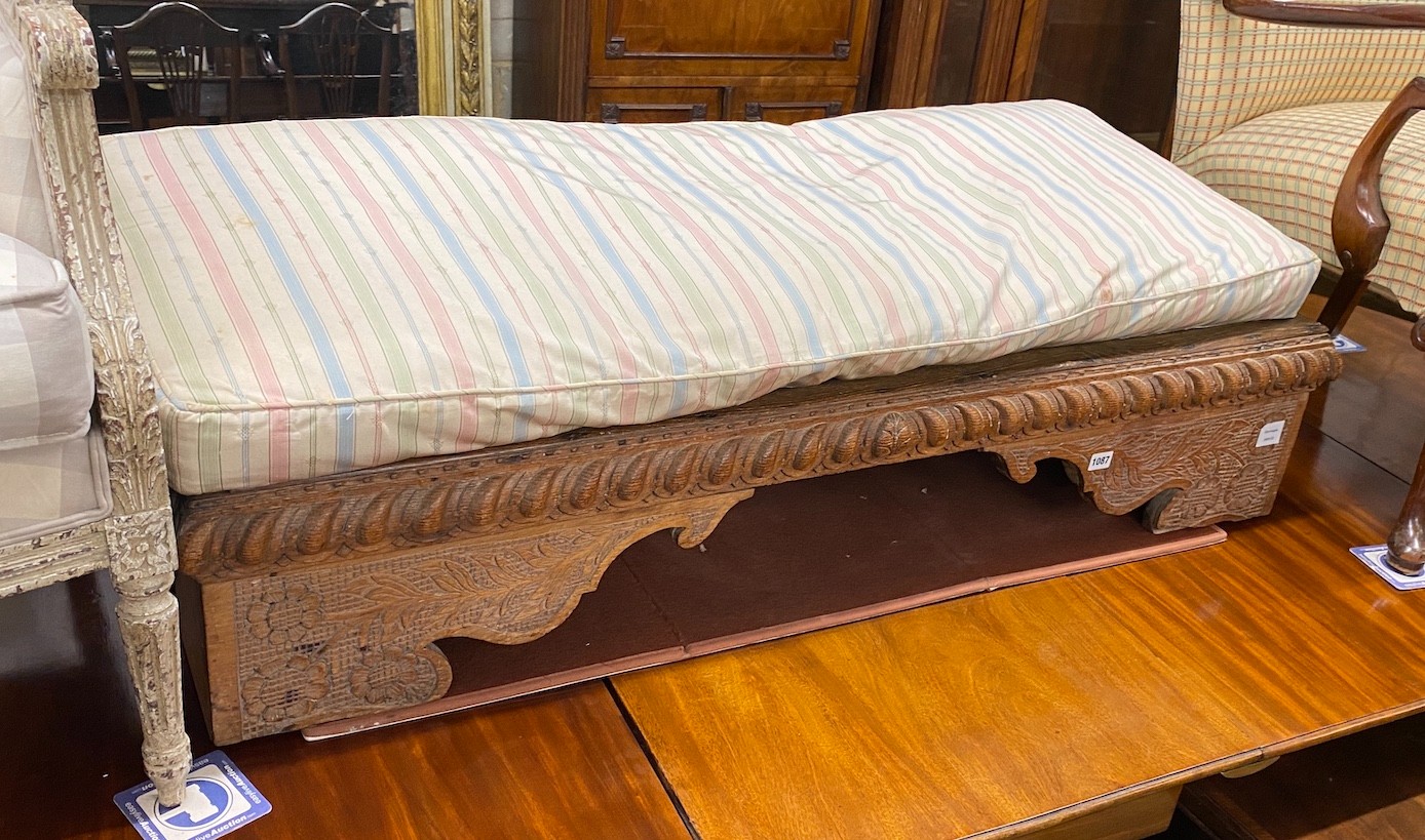 A 19th century Spanish oak low stool, length 134cm, depth 46cm, height with cushion 40cm